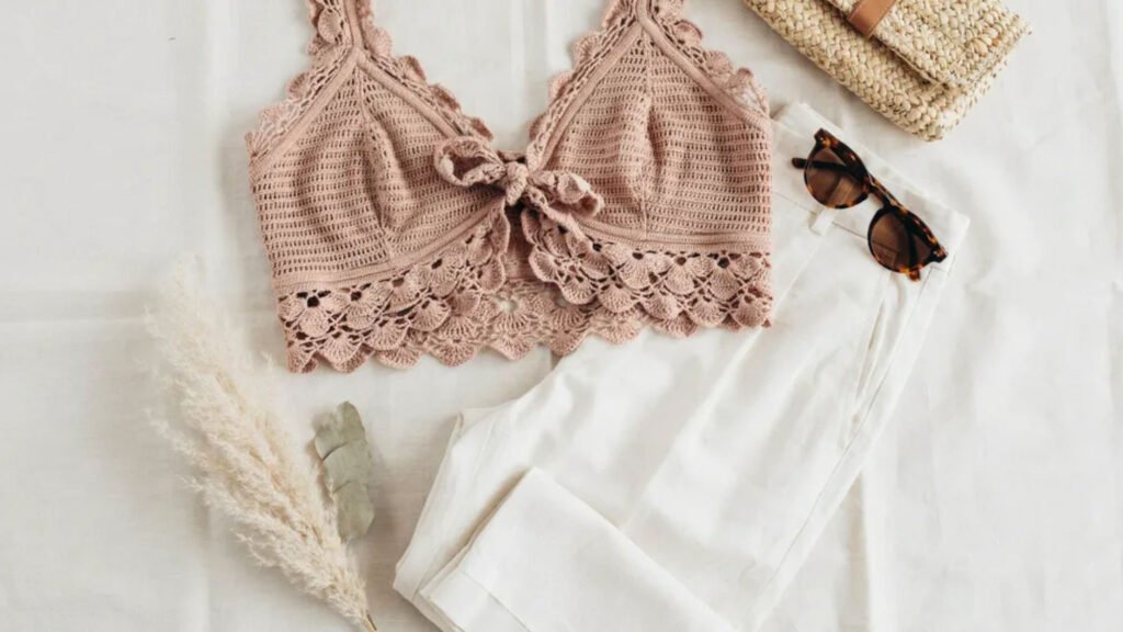 Sage green crochet camisole with thin straps and simple fitted body displayed as a flat lay on white marbl
