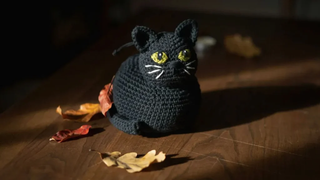 Halloween black cat crochet bag pattern with bright embroidered eyes for a spooky look