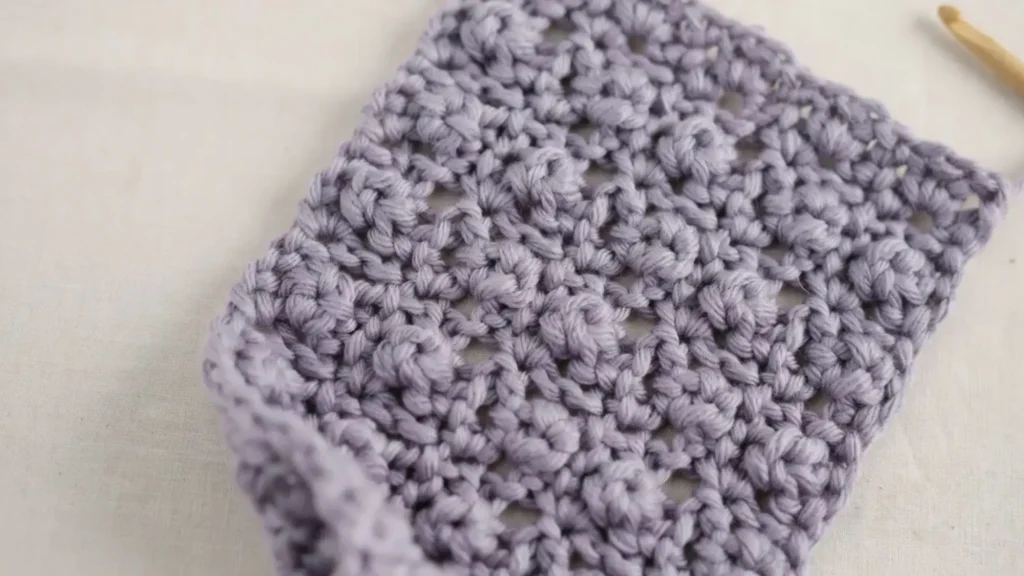Boxed puff stitch crochet swatch with puffs framed in chain squares.