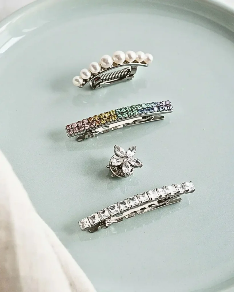 Four hair clips decorated with pearls, rainbow rhinestones, flowers, and geometric crystals.