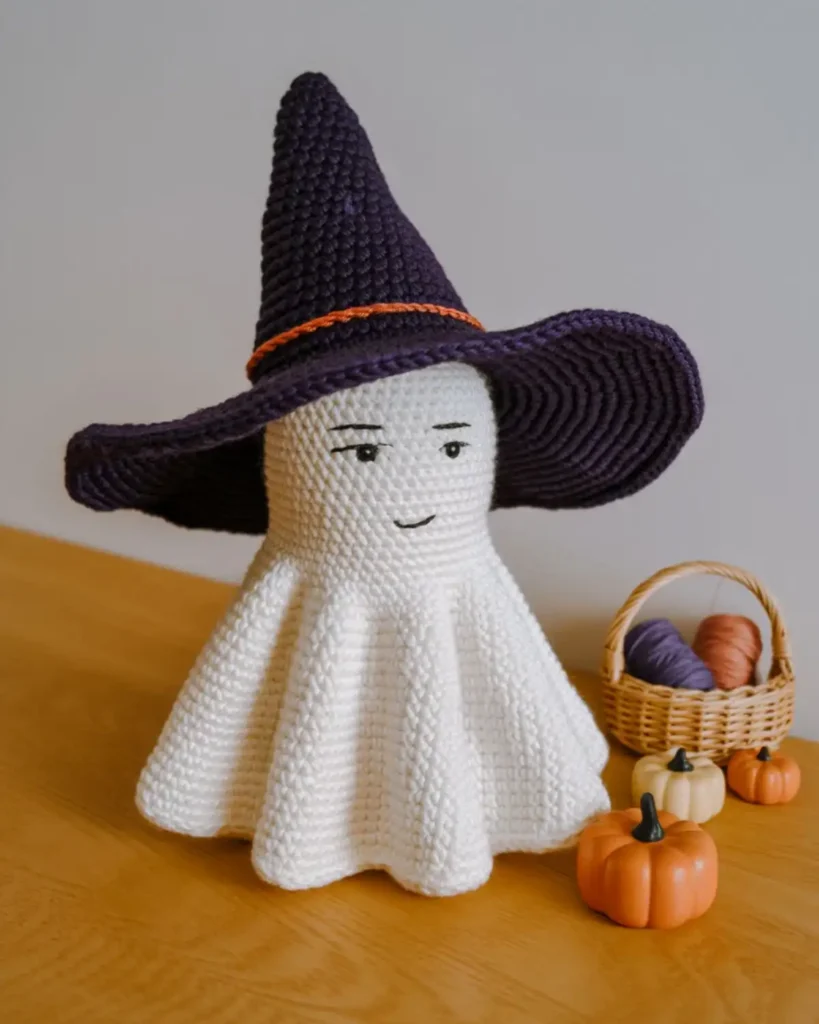 White crochet ghost wearing a black witch hat with an orange band.