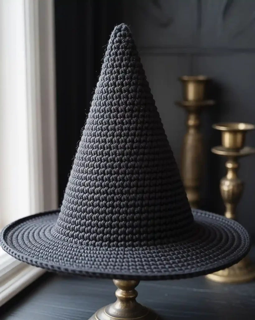 Classic black crochet witch hat with a tall pointed cone and structured wide brim.