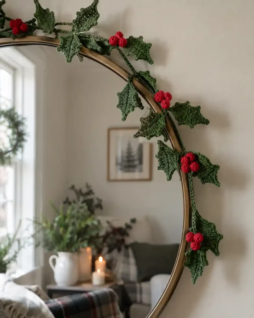 A full-size forest-green crochet wreath with holly leaves, red yarn berries and a cream crochet bow centered on an interior wooden door.