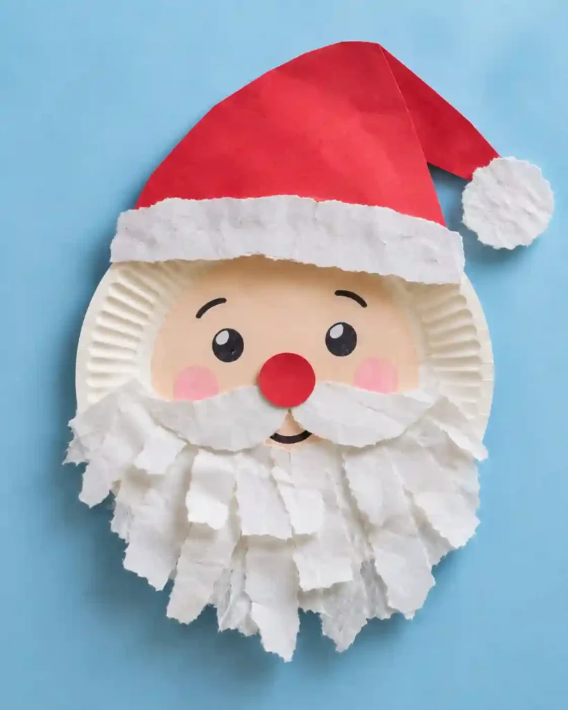 Three upright cardboard tube snowmen wrapped in white paper with drawn faces and bright paper scarves on a wooden shelf.