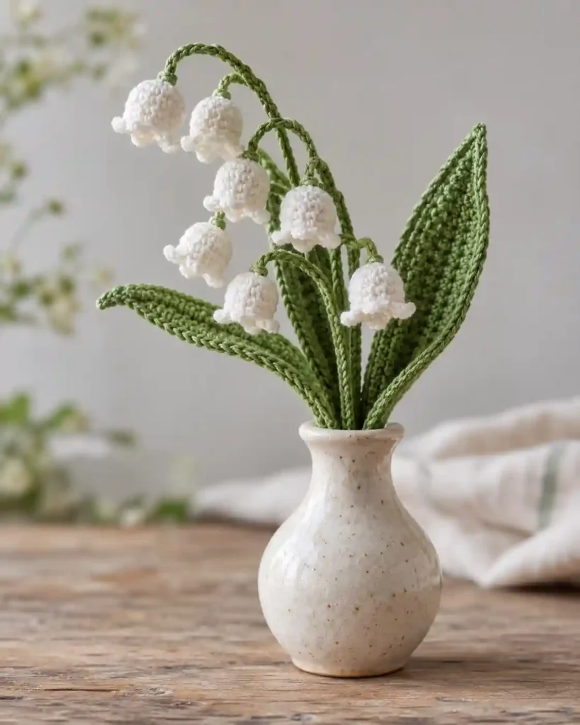 Handmade delicate lily-of-the-valley sprig photographed as a crochet Mother’s Day gift, with clear stitching and an uncluttered background.