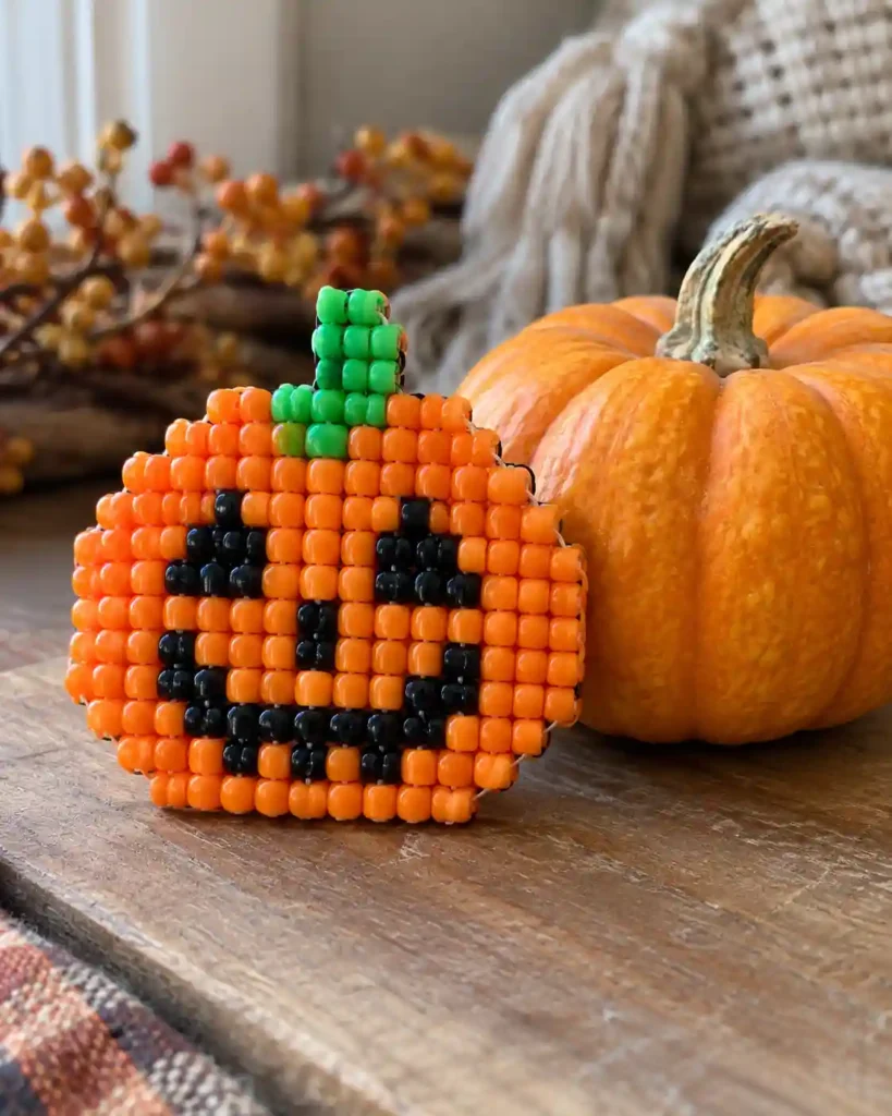 Handmade pony bead tapestry showing friendly jack-o-lantern face in a flat pixel-grid panel.