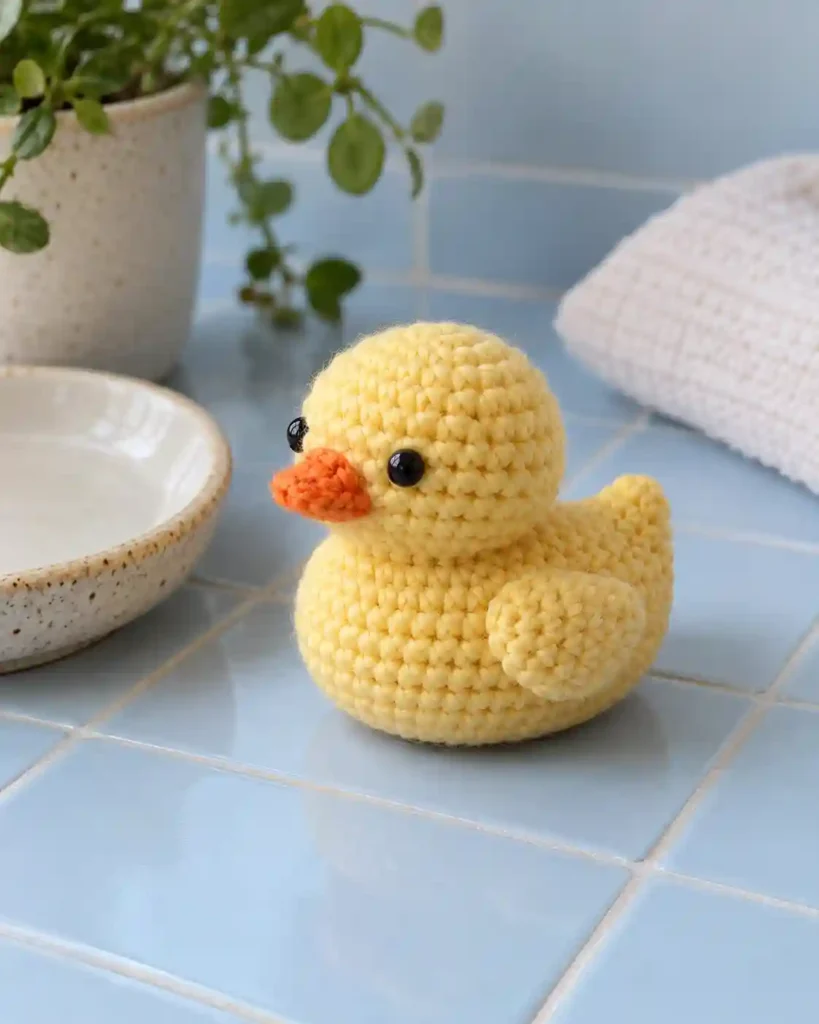 Finished chubby duck crochet amigurumi showing its distinct shape and no-sew integrated details in a clean craft setting.